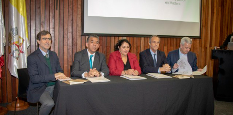  Director del CIM, Juan José Ugarte junto a cuatro personas, tres hombres y una mujer en una mesa firmando convenio para la construcción de Villa Ecosustentable Mininco
