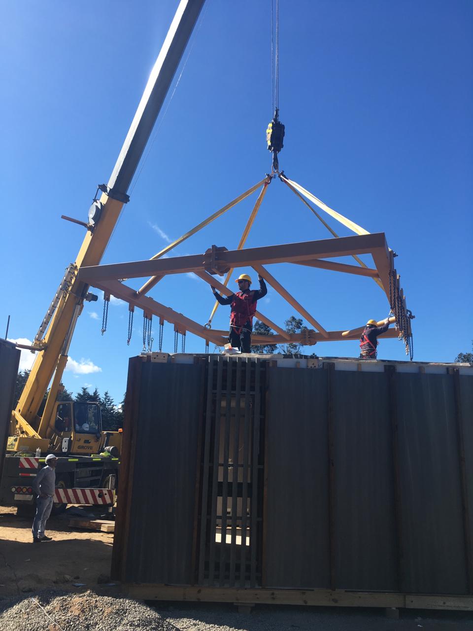 trabajos del montaje oficial de la Torre Experimental Peñuelas. Dos trabajadores sostienen la estructura del techo de la torre que sostiene una grúa